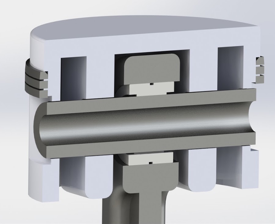 Section view of the piston showing the crown, three ring grooves, the wrist pin and the top of the connecting rod