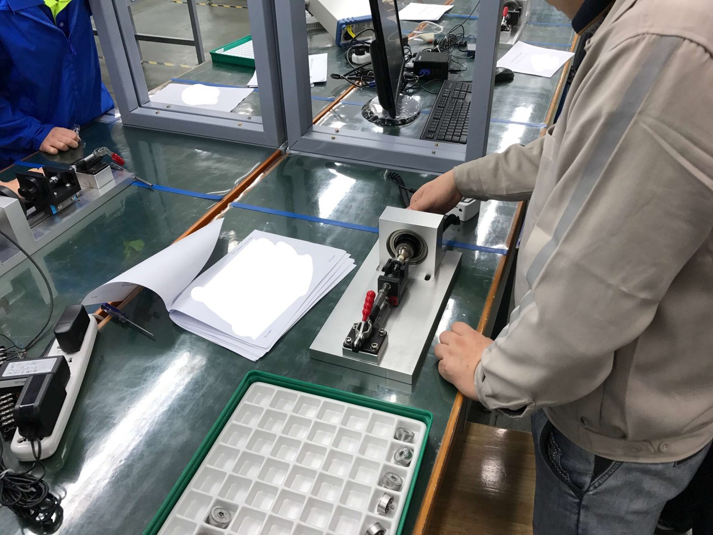 An operator at the vendor's line running the bezel fixture while their procedure is reviewed