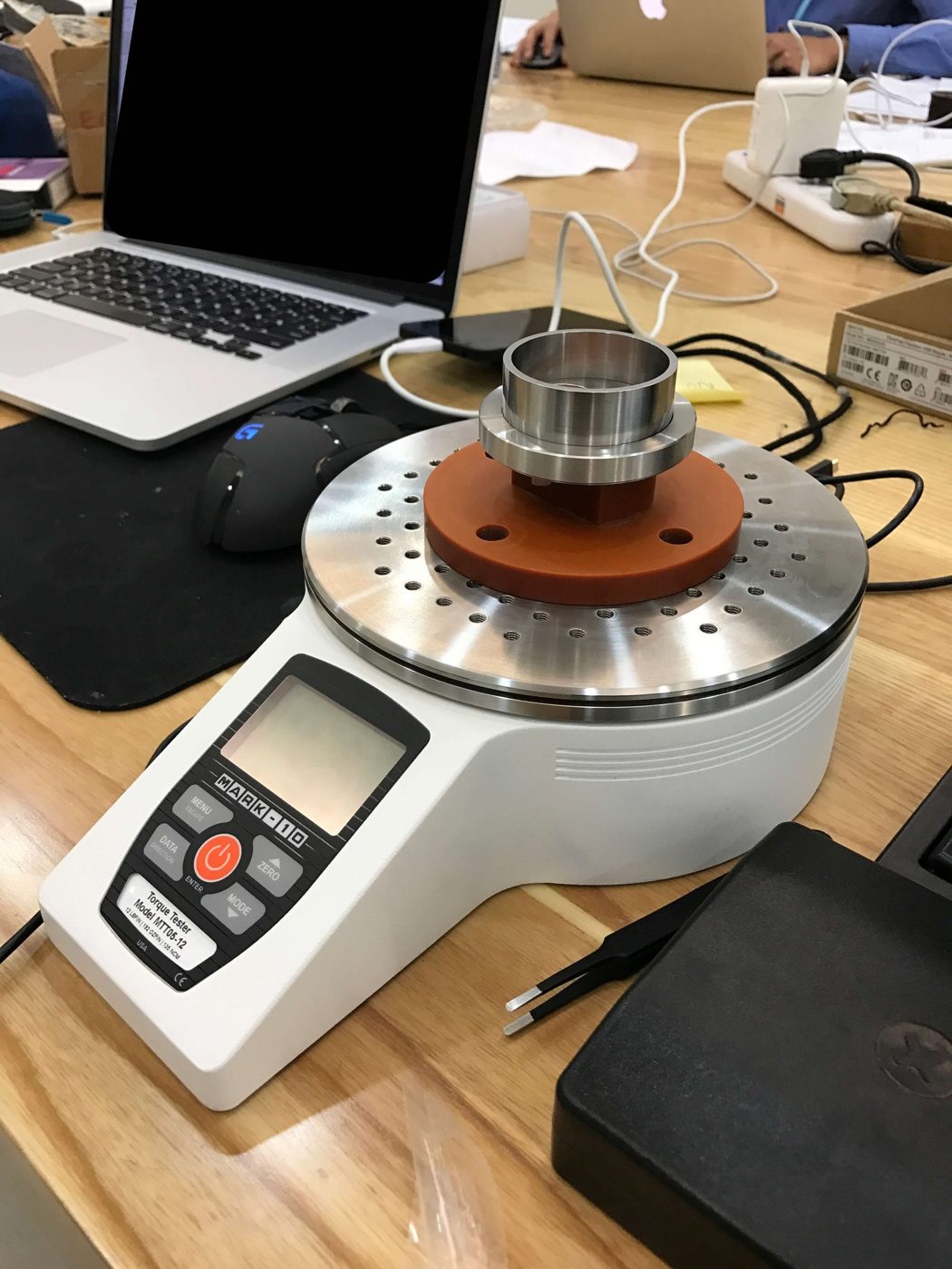 Mark-10 desktop torque tester with a custom orange mounting plate holding the eject bezel